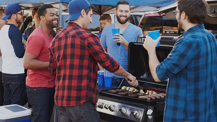 Friends around a grill at a tailgate