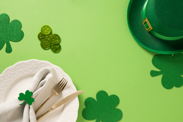 St Patrick's Day table setting with white plate and clover leaves on green.