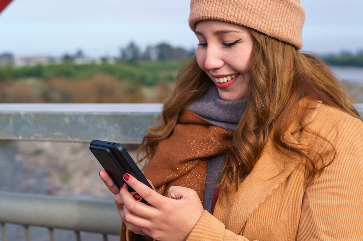 Latin woman using smartphone on a bridge in autumn