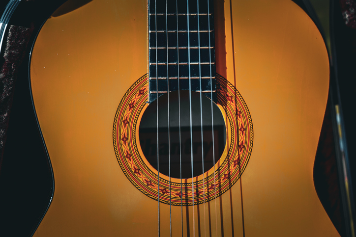Close-up of a classical acoustic guitar, highlighting its sound hole, strings, and fretboard